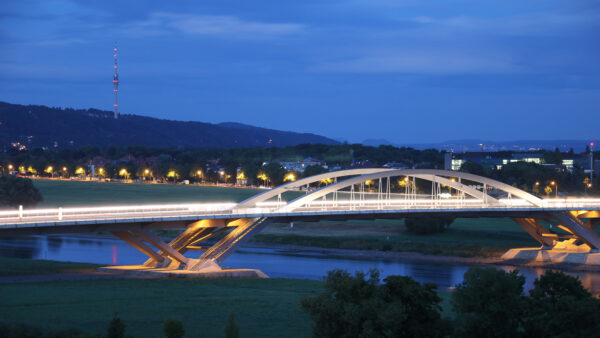 Die Waldschlösschenbrücke Dresden überspannt die Elbe, fotografiert in der blauen Stunde. Im Hintergrund sind das Käthe-Kollwitz-Ufer und die Elbhänge mit Dresdner Fernsehturm zu sehen.