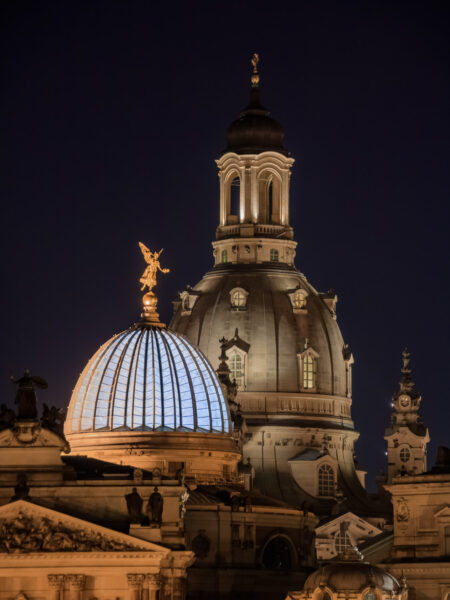 Nachtfotografie von der Dresdner Carolabrücke aus. Der Blick fällt auf die erleuchtete Zitronenpressenkuppel der Kunstakademie mit ihrem goldenen Engel sowie der Kuppel der Frauenkirche etwas dahinter.