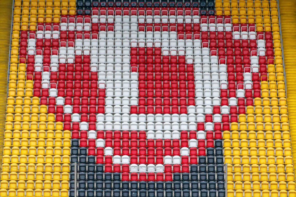 Aus dem K-Block des Rudolf-Harbig-Stadions in Dresden geht der Blick hinüber in den Block B, in dem die Sitzschalen das Logo der SG Dynamo Dresden zeigen, jedoch ohne die Banderole mit dem "DRESDEN"-Schriftzug.