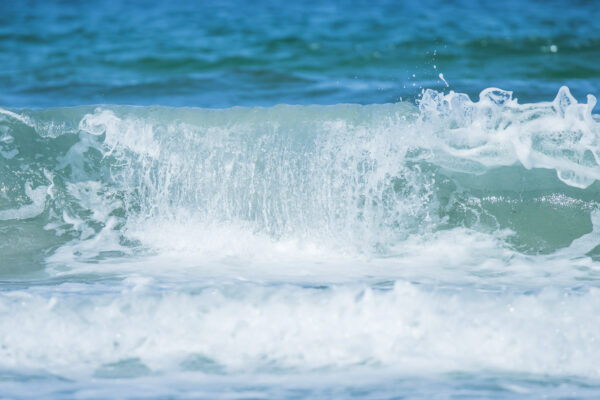 Ein leichter Wellengang der Ostsee führt zu immer wieder interessanten Wellenformationen, die mit einer sehr kurzen Belichtungsdauer eingefroren wirken. Ein Teil der Welle stürzt gerade in sich zusammen, während sie sich am Rand noch hält und eine leichte Schaumkrone mit sich führt.